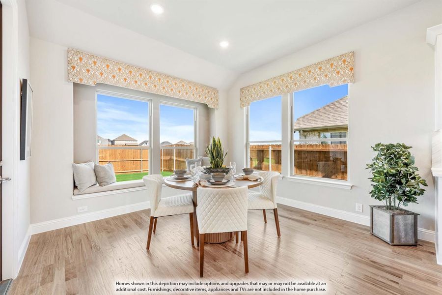 Bright breakfast nook with round dining table, window seat, and large windows overlooking backyard Bright breakfast nook with round dining table, window seat, and large windows overlooking backyard