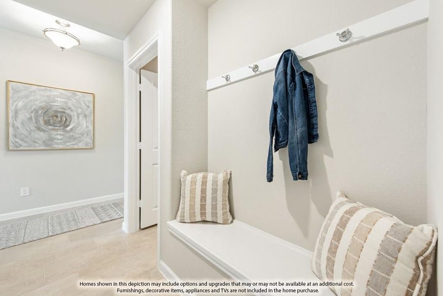 Mudroom entryway with built-in bench, wall hooks, and tile flooring