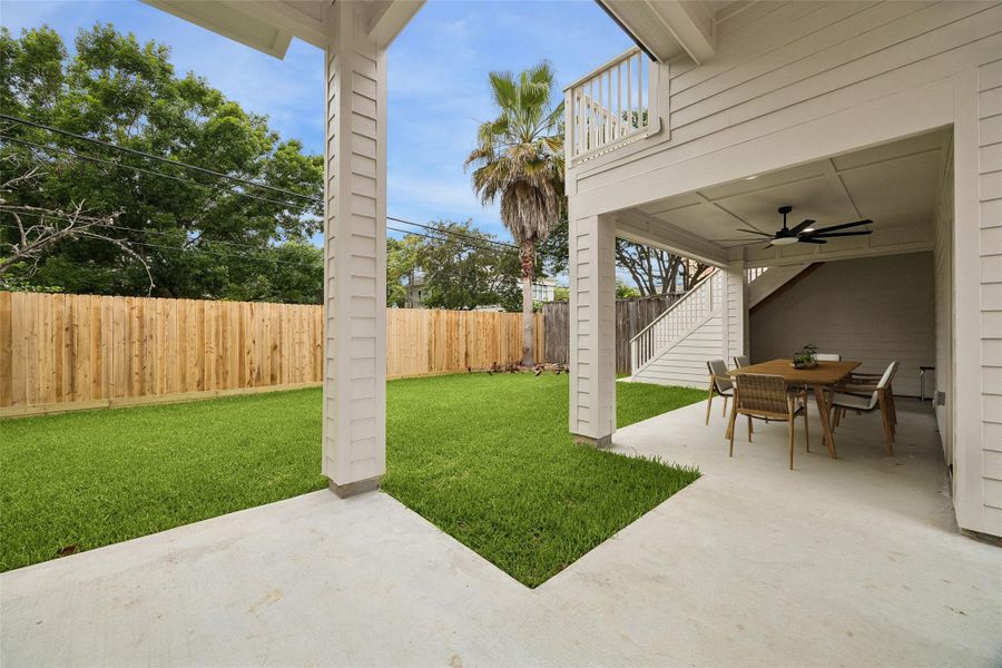 The covered outdoor entertaining area provides shaded seating space beneath the elevated terrace while maintaining direct access to the backyard and garage apartment. The layout was designed to support indoor-outdoor living across multiple levels of the property.