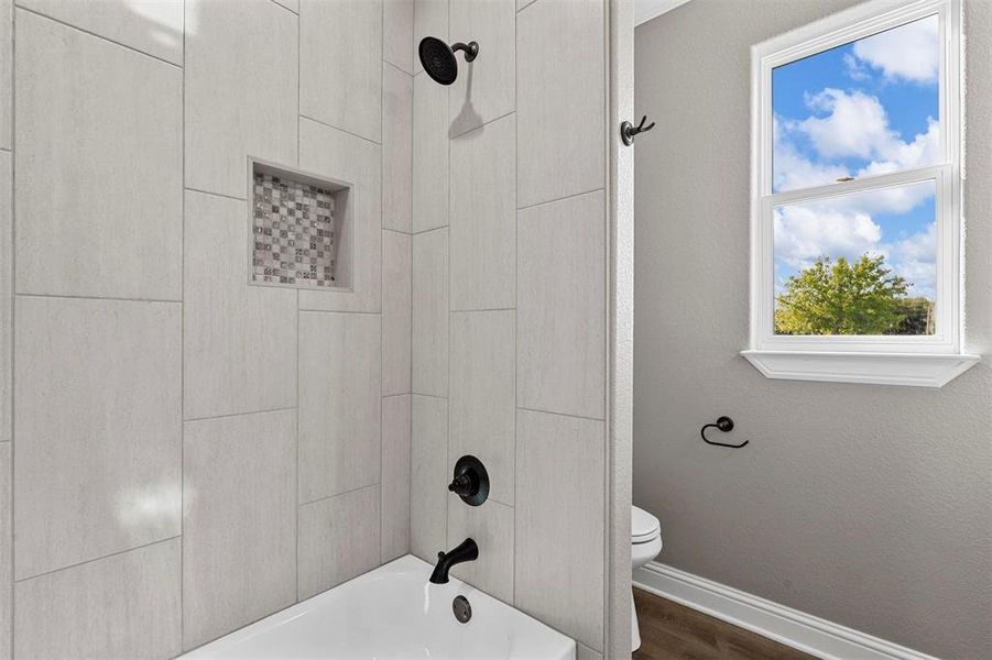 Bathroom featuring toilet, hardwood / wood-style floors, and shower / bathing tub combination