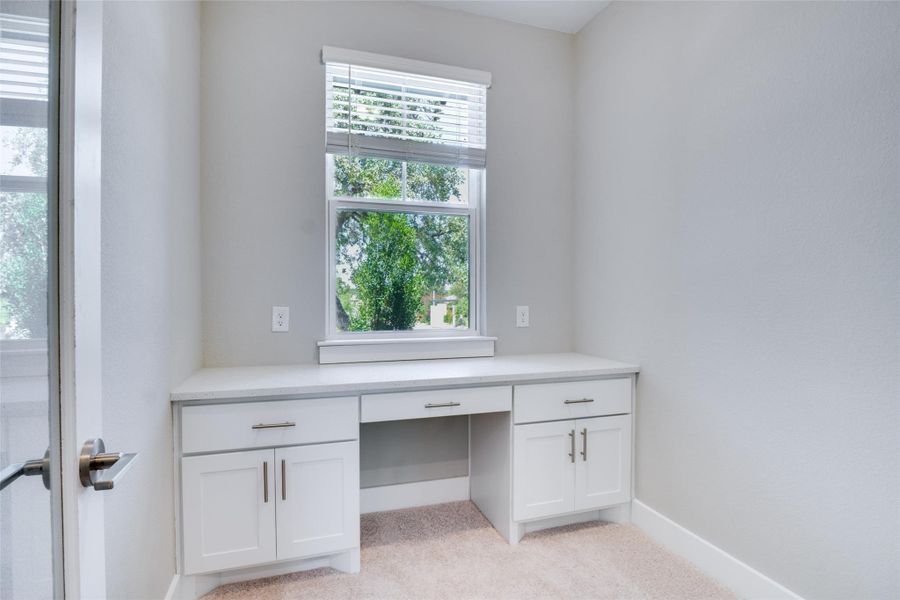 Unfurnished office featuring light carpet and built in desk