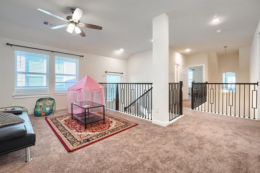 Living area with carpet, ceiling fan, and vaulted ceiling