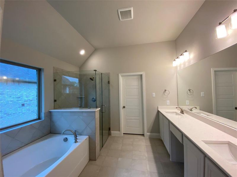 Bathroom featuring vanity, separate shower and tub, and vaulted ceiling