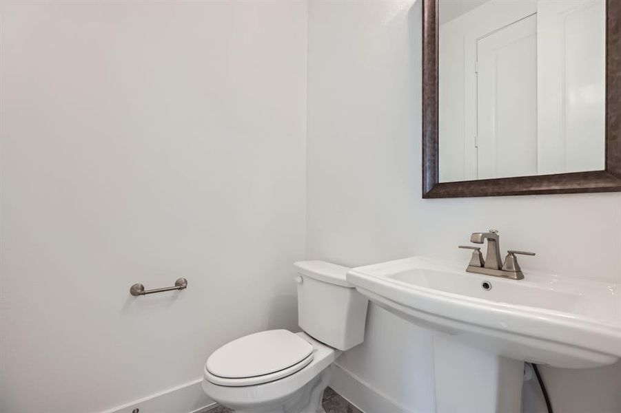 Bathroom featuring baseboards, toilet, and a sink
