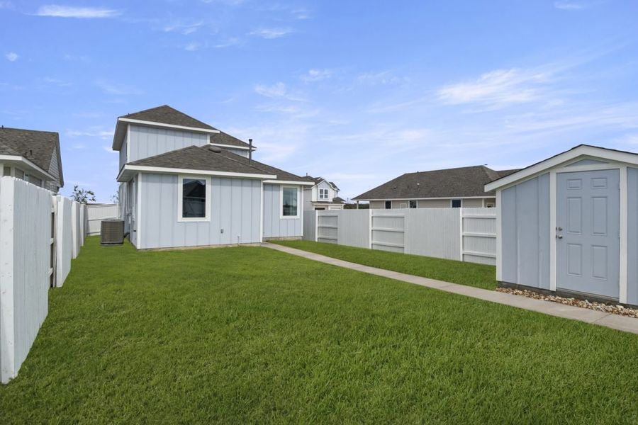 Image of the back exterior of a two story grey home with a pathway and a green grass backyard Image of the back exterior of a two story grey home with a pathway and a green grass backyard