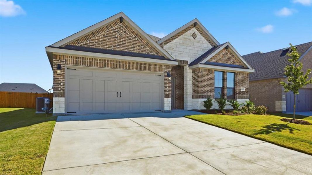 View of front of property featuring brick siding, driveway, a garage, and stone siding