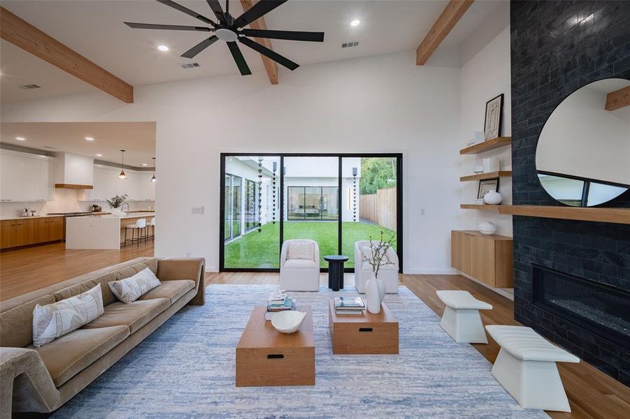 Living room with ceiling fan, beamed ceiling, high vaulted ceiling, a fireplace, and light wood-type flooring