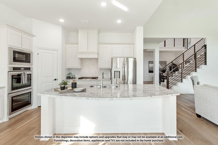 White kitchen with large curved island, granite countertops, stainless steel appliances, and hardwood floors