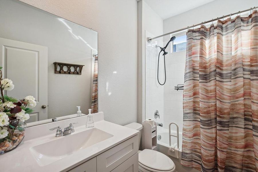 Full bathroom featuring vanity with extensive cabinet space, toilet, and shower / bath combo Full bathroom featuring vanity with extensive cabinet space, toilet, and shower / bath combo
