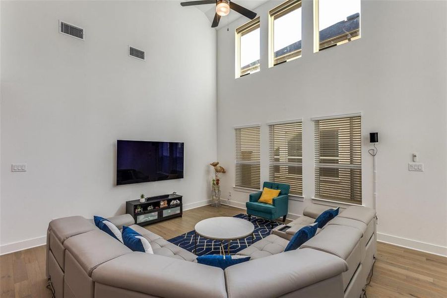 Living area with light wood-type flooring, a ceiling fan, and a high ceiling Living area with light wood-type flooring, a ceiling fan, and a high ceiling