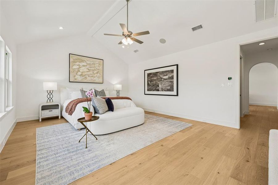 Spacious room featuring vaulted ceilings, light wood-finish flooring, recessed lighting, and an arched hallway entry