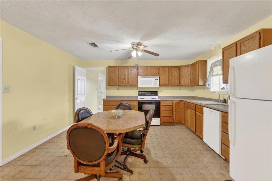Spacious kitchen featuring a ceiling fan, wood-finish cabinetry, and white appliances
