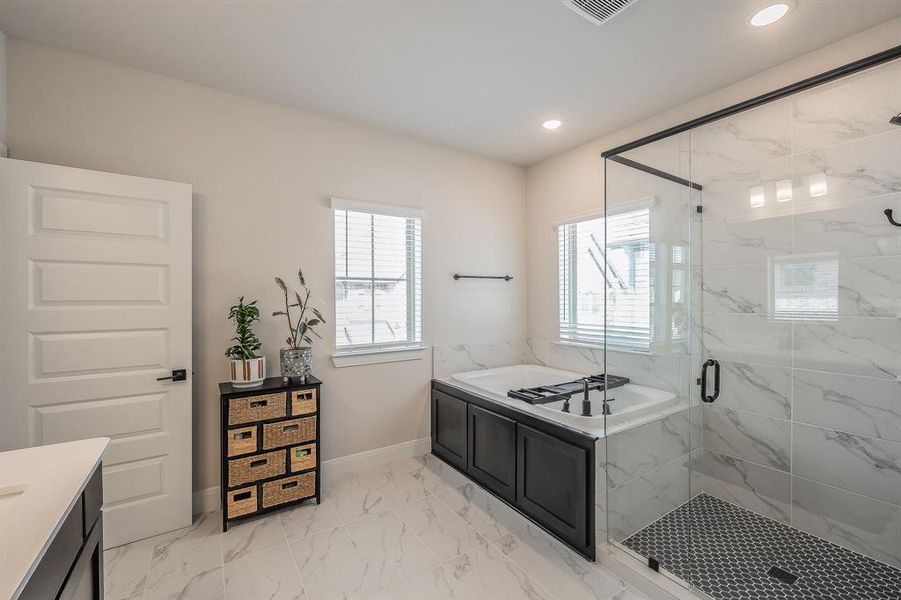 Bathroom with a bath, a marble finish shower, light marble finish flooring, vanity, and recessed lighting