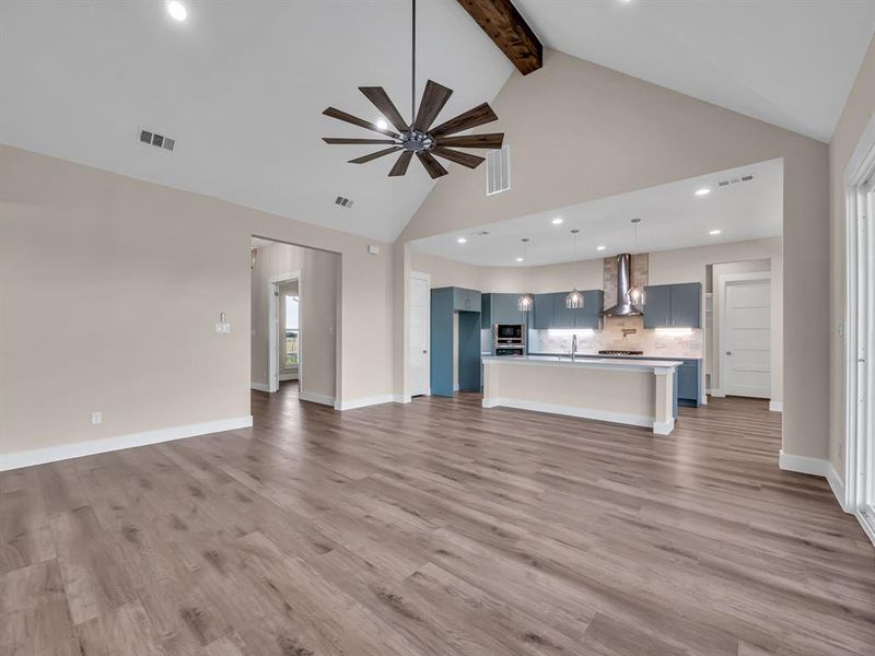 Unfurnished living room featuring beamed ceiling, sink, light wood-type flooring, high vaulted ceiling, and ceiling fan