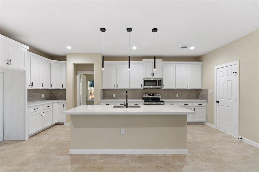 Kitchen featuring white cabinets, a kitchen island with sink, hanging light fixtures, and appliances with stainless steel finishes