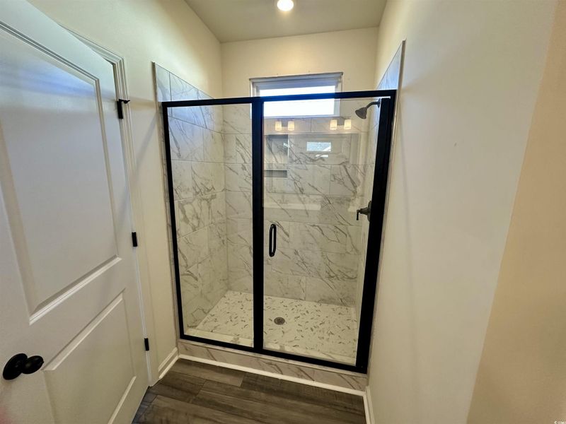 Bathroom with a tile shower and dark wood-style floors Bathroom with a tile shower and dark wood-style floors