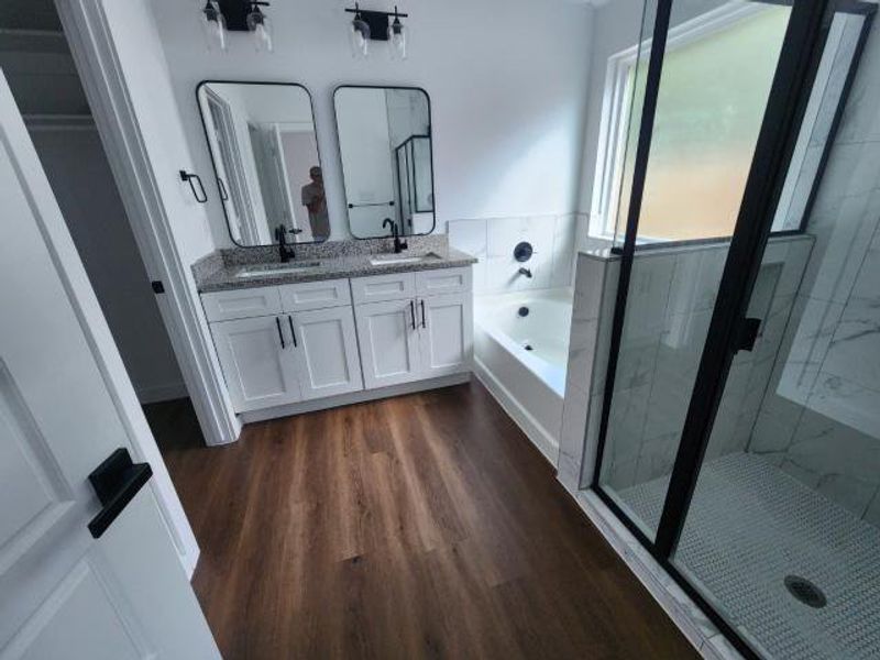 Bathroom featuring a stall shower, a garden tub, double vanity, and dark wood-type flooring Bathroom featuring a stall shower, a garden tub, double vanity, and dark wood-type flooring