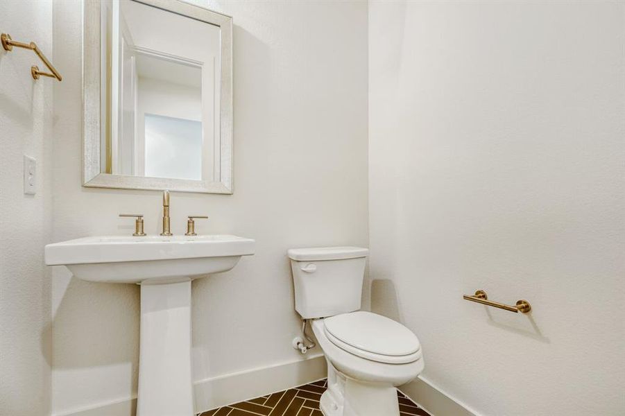 Half bath with toilet and dark tile patterned flooring