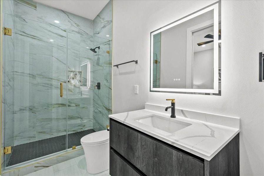 This beautifully finished full bath offers LED accent lighting and a sleek walk-in shower with gorgeous tile details — truly elevated.