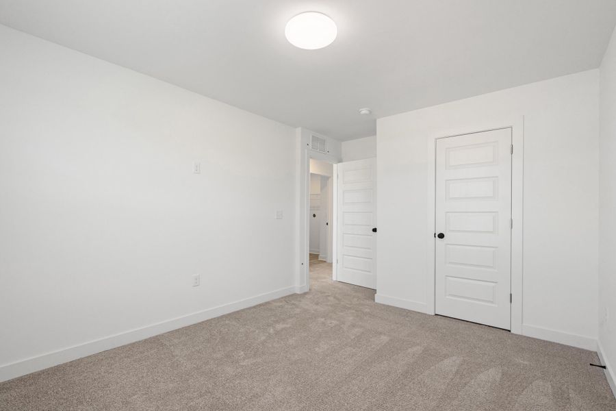 Neutral tone wall paint, carpet flooring, flush mount ceiling light, and paneled interior doors