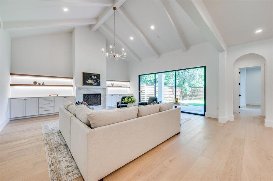 Living area featuring arched walkways, recessed lighting, beam ceiling, light wood-type flooring, and high vaulted ceiling Living area featuring arched walkways, recessed lighting, beam ceiling, light wood-type flooring, and high vaulted ceiling