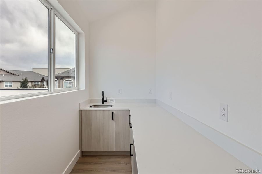 Wet bar on 3rd level with beverage fridge and large sliding window that opens to the rooftop deck for convenient entertaining.(NOTE: This home has a darker color scheme. See finishes for details.)