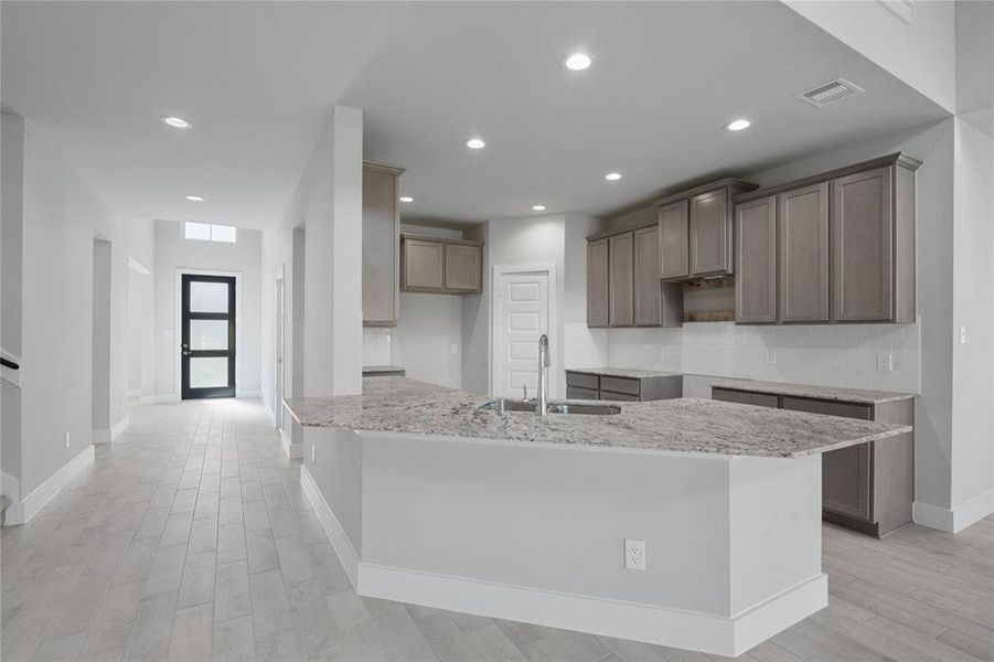 This stunning kitchen displays beautiful cabinets, custom neutral paint, granite countertops, light modern backsplash, and SS appliances, oversized kitchen with extra storage, breakfast bar, recessed lighting, high ceilings and pantry.