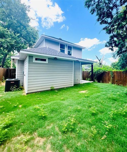 Back of property featuring central AC unit and a yard