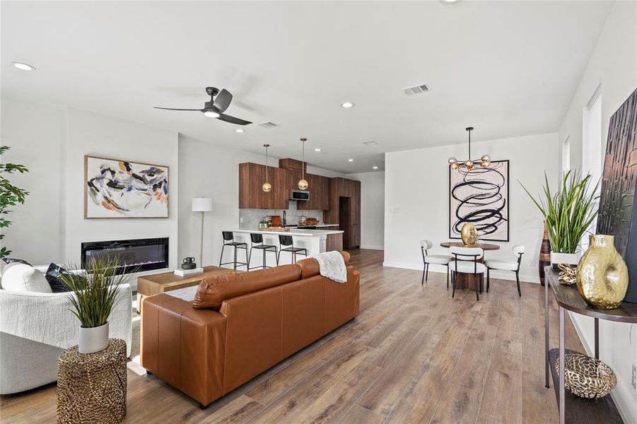 Living room with light hardwood / wood-style flooring and ceiling fan with notable chandelier