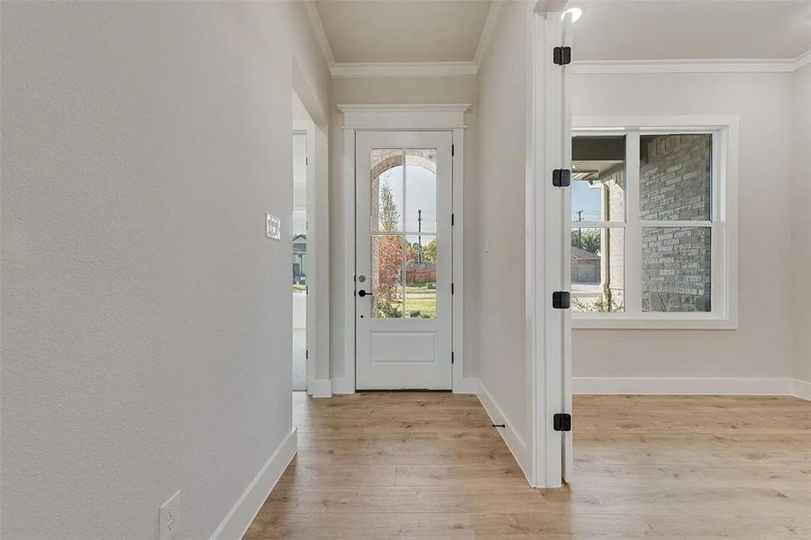 Doorway to outside with hardwood / wood-style flooring and ornamental molding