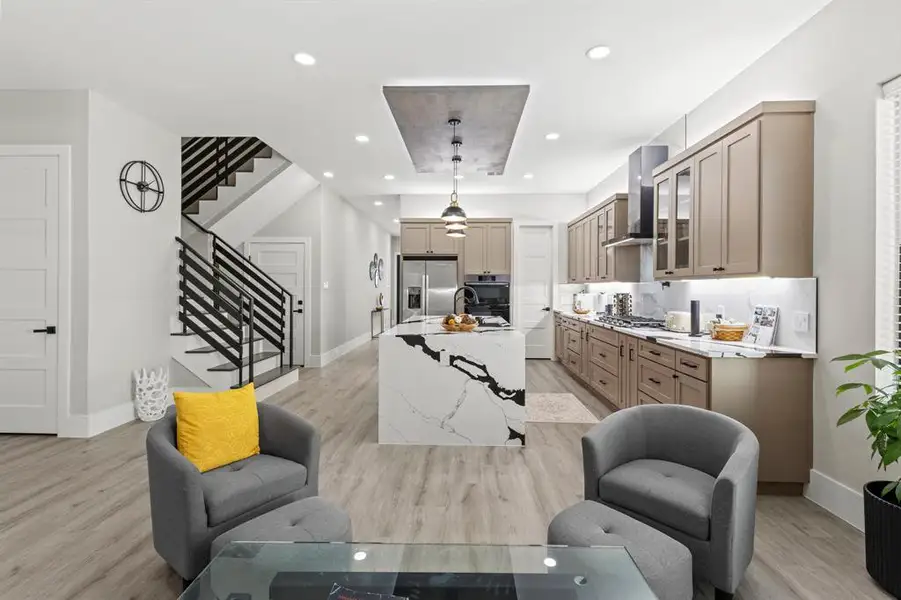Kitchen featuring light stone counters, recessed lighting, hanging light fixtures, a center island with sink, and glass insert cabinets