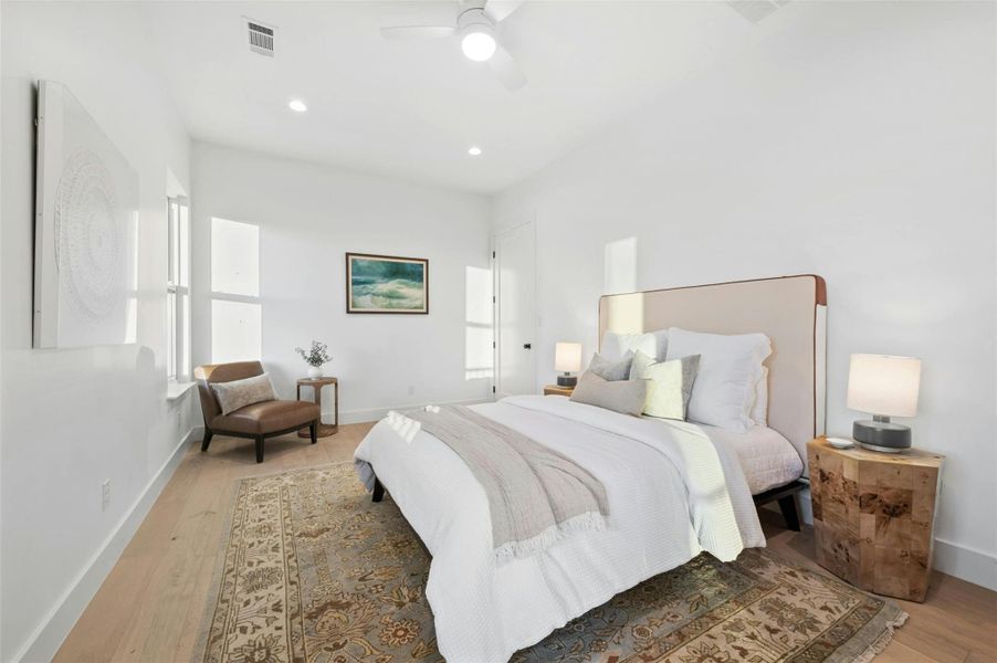 One of two dedicated secondary bedrooms on the first floor, each with modern ceiling fans, recessed lighting, and closet storage.