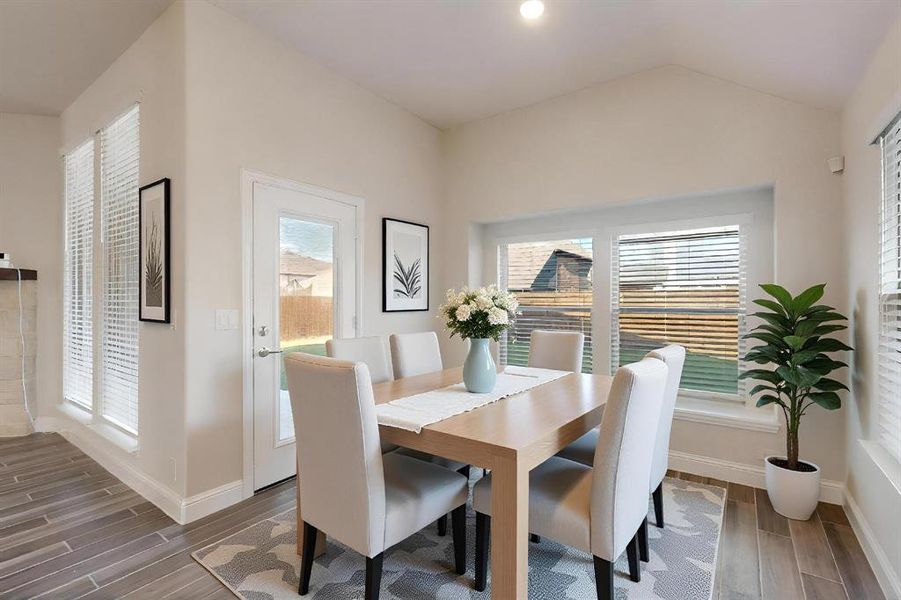 Dining room with healthy amount of natural light, wood finish floors, recessed lighting, and vaulted ceiling