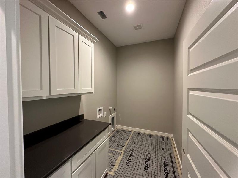 Washroom with electric dryer hookup, tile patterned flooring, cabinets, and washer hookup