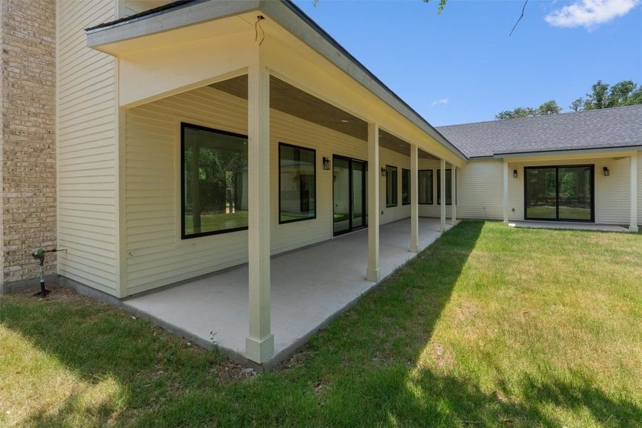 A deep covered patio spans the length of this residence, offering shade and an ideal setting for outdoor enjoyment.