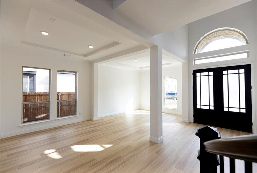 Foyer entrance featuring french doors, a tray ceiling, and light hardwood / wood-style floors