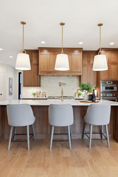 Kitchen featuring brown cabinets, pendant lighting, a kitchen bar, tasteful backsplash, and light wood finished floors