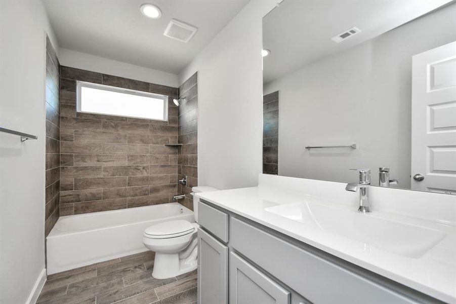 Experience sophistication in the secondary bathroom, where tile flooring complements a bath/shower combo with tile surround. Slate wood cabinets complete with a beautiful light countertop, enhances the space for a truly inviting ambiance. Sample photo of completed home with similar floor plan. As-built interior colors and selections may vary.