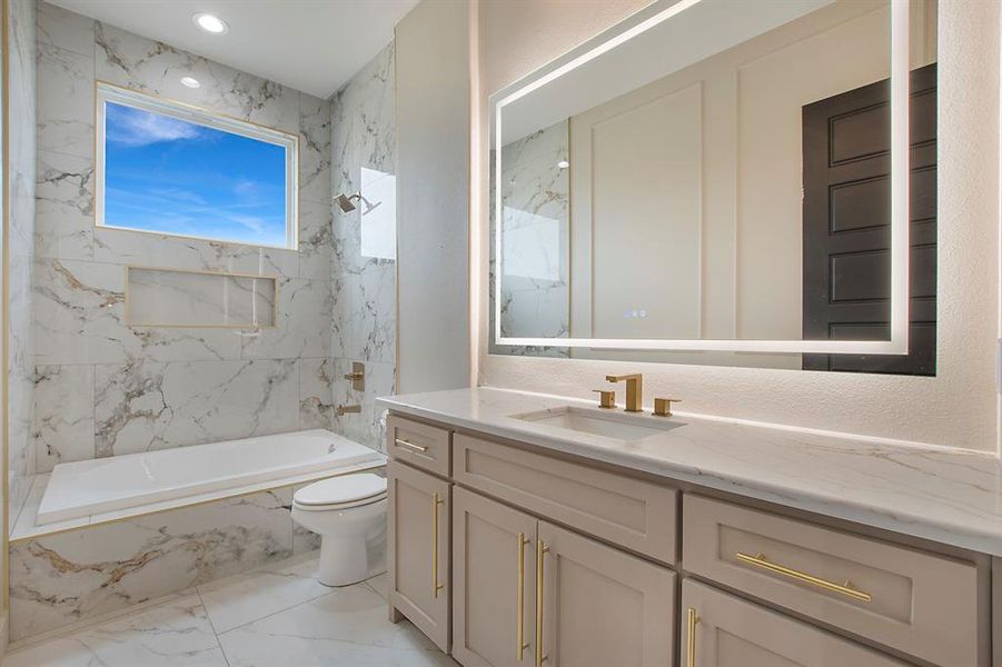 Full bathroom featuring vanity, tiled shower / bath combo, and toilet