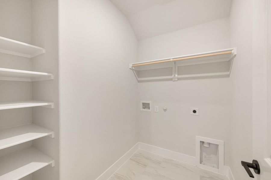 Laundry room with white walls, built-in shelving, hanging rod, and washer and dryer hookups on marble tile floor