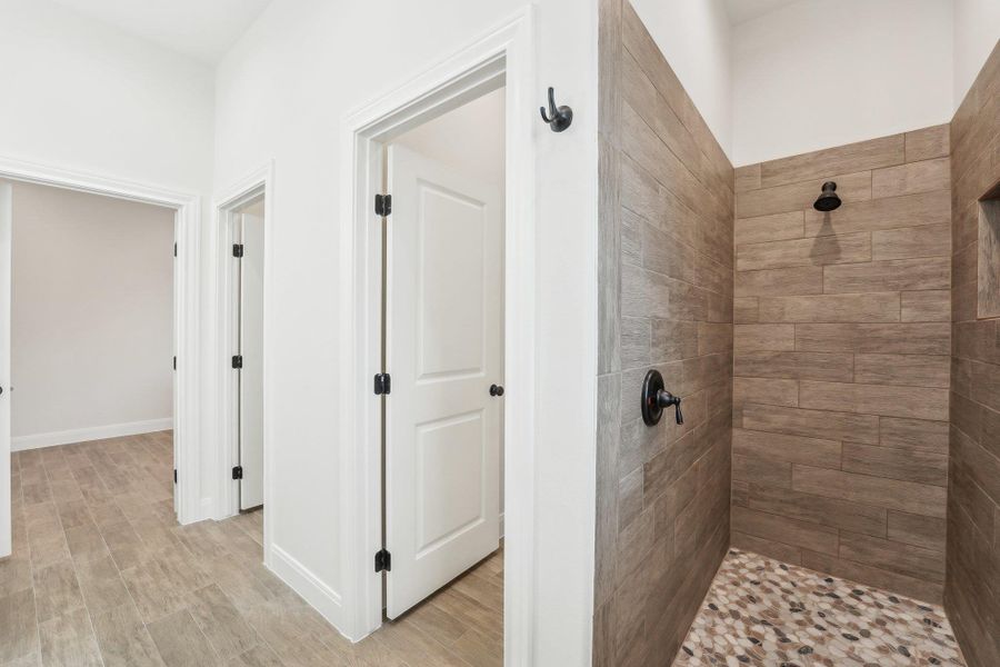 Full bath featuring a tile shower, baseboards, and wood plank tile floor Full bath featuring a tile shower, baseboards, and wood plank tile floor