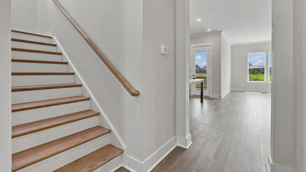 Stairway featuring elevated features such as accented wood and railing before you enter the kitchen area.