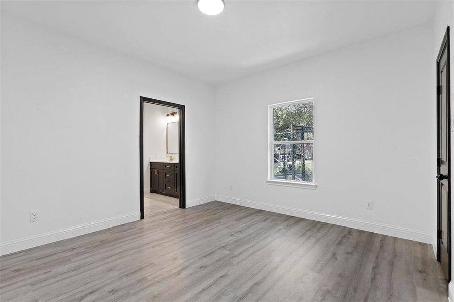 Unfurnished bedroom featuring light hardwood / wood-style floors and ensuite bathroom