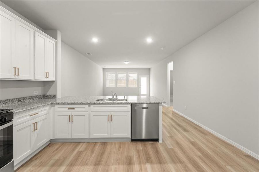 Kitchen featuring stainless steel dishwasher, white cabinets, kitchen peninsula, and sink