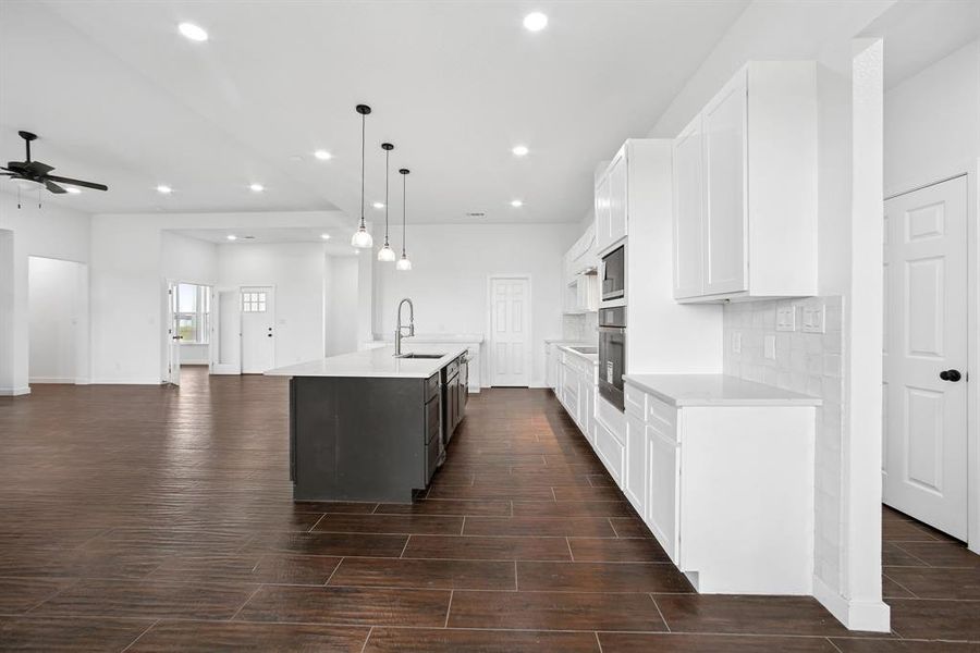 Kitchen featuring tasteful backsplash, white cabinets, decorative light fixtures, wood finish floors, and recessed lighting