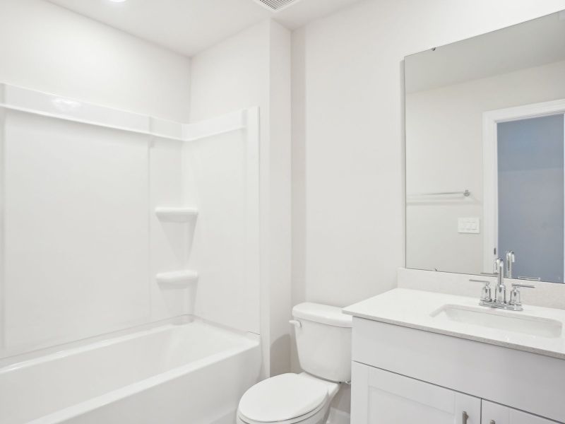 The secondary bathroom features a large vanity and oversized shower tub.
