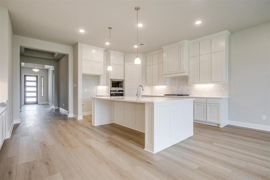 Kitchen featuring a kitchen island with sink, white cabinetry, light hardwood / wood-style flooring, and appliances with stainless steel finishes