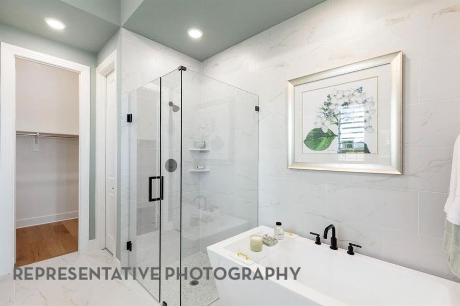 Bathroom with a spacious closet, a shower stall, a freestanding bath, and recessed lighting