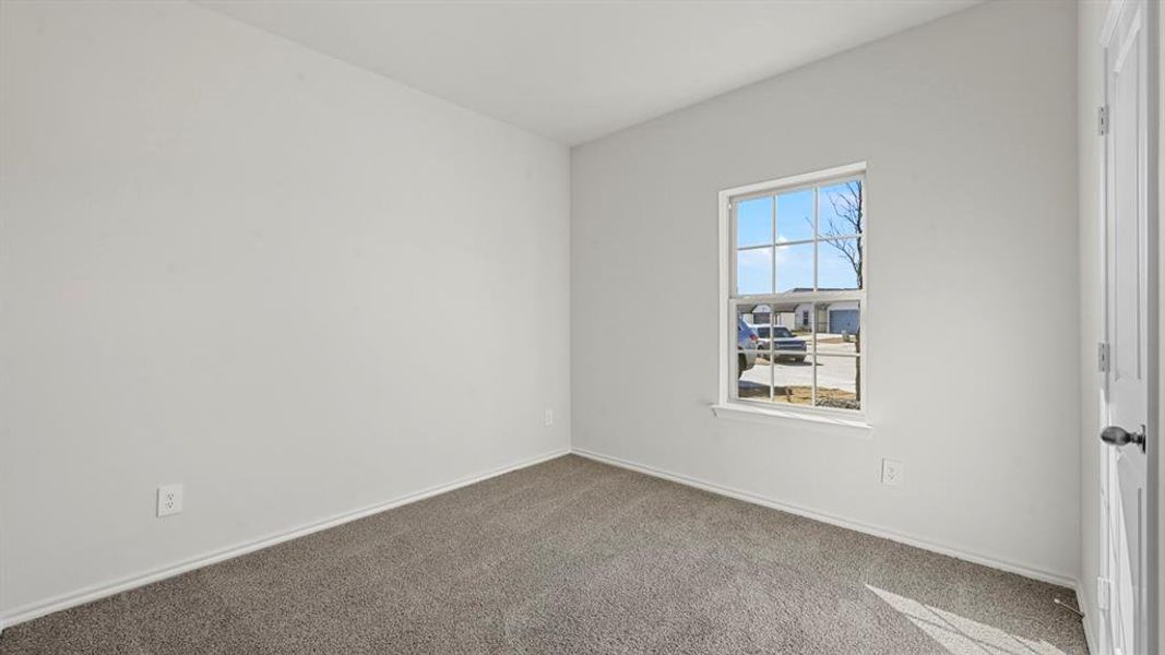Neutral-toned room featuring a single window with white trim, light gray carpeting, crisp white walls, and a white paneled door with a black knob