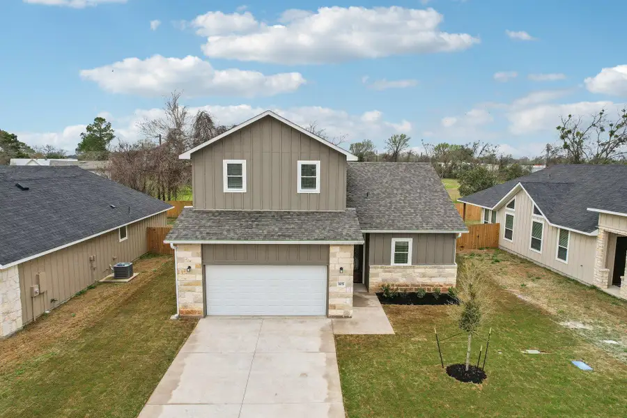 Traditional home featuring cooling unit, stone siding, board and batten siding, and a front yard Traditional home featuring cooling unit, stone siding, board and batten siding, and a front yard